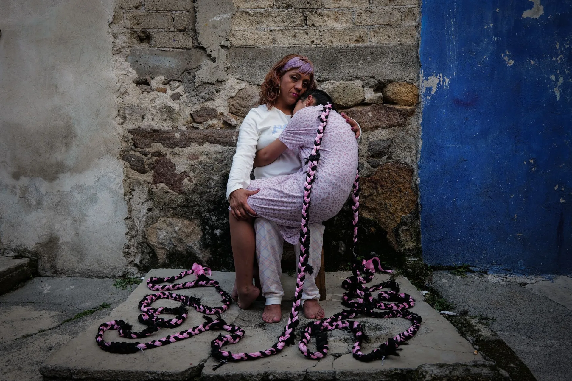 Woman seated with pink textile by a blue door